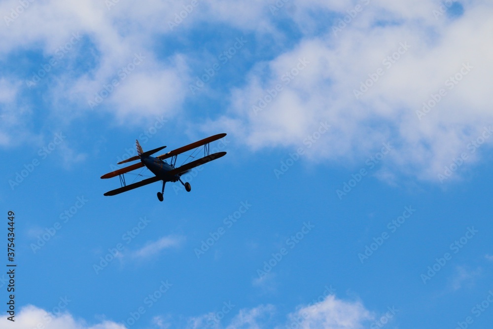 Fototapeta premium alter Doppeldecker fliegt vor blauem Himmel