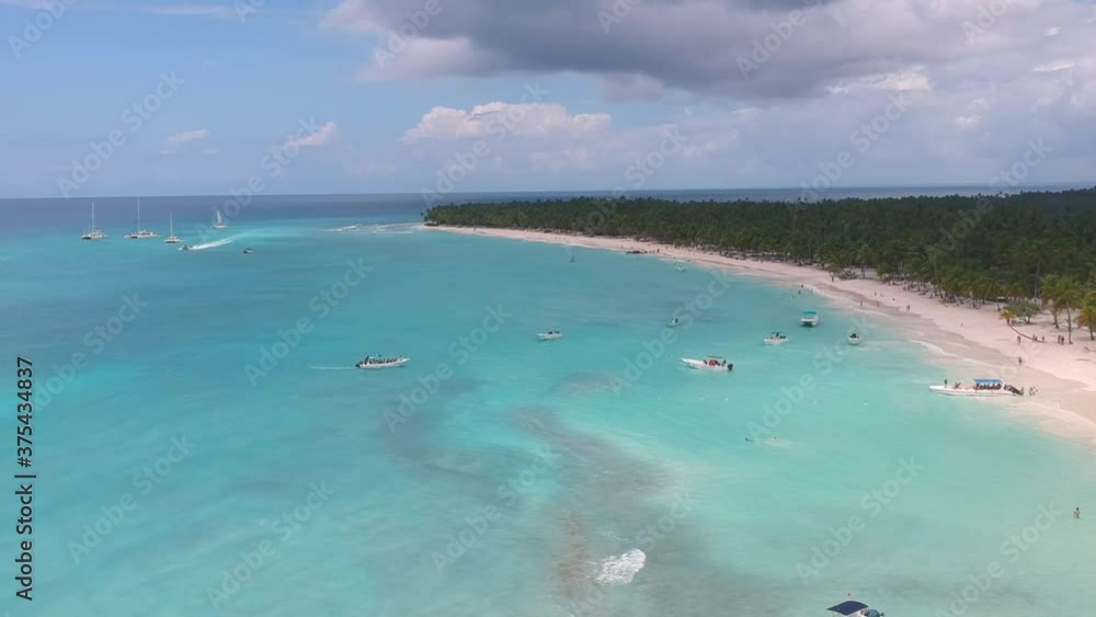 Drone shot showing the shoreline and boats coming and going in Saona Island (Dominican Republic) In a sunny day hitting the blue waters of the caribbean Drone shot showing the shoreline and boats coming and going in Saona Island (Dominican Republic) In a sunny day hitting the blue waters of the caribbean