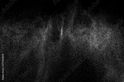 Abstract splashes of water on black background. Freeze motion of white particles. Rain, snow overlay texture.