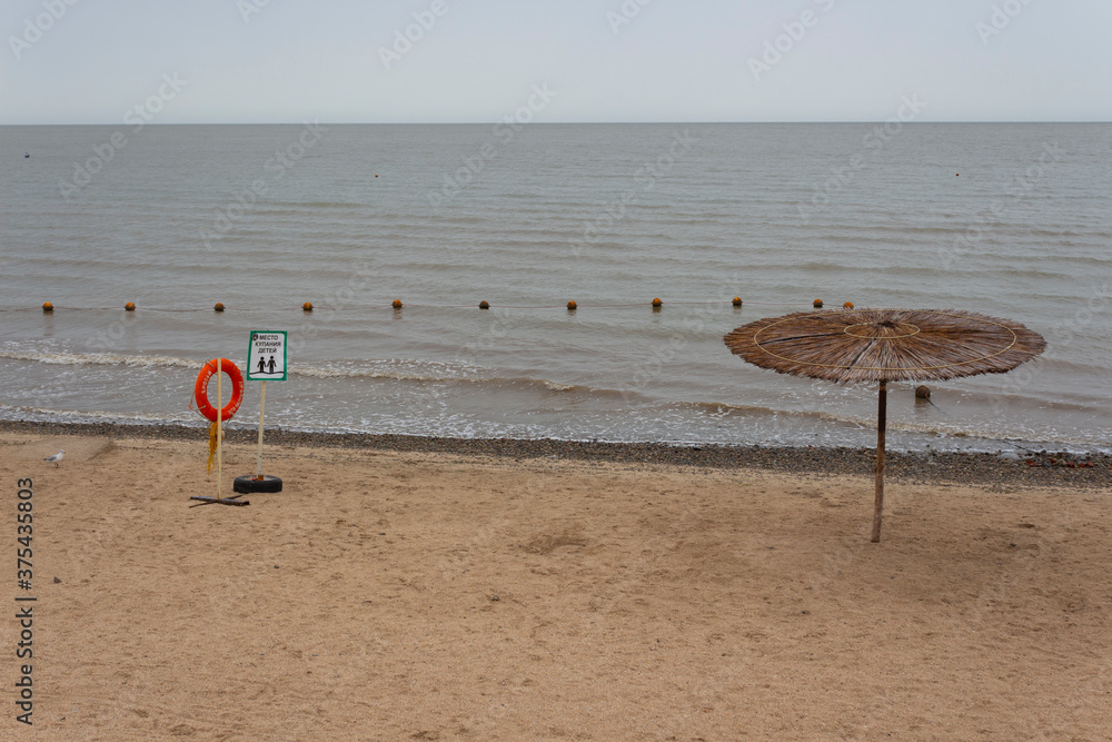 Obraz premium Empty beach on a cloudy cool day. The inscription on the lifebuoy 