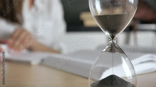 close-up hourglass. Silhouette woman reading a book and write conspectus on a blurred background 4k