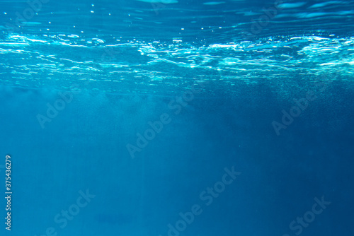 Fototapeta Naklejka Na Ścianę i Meble -  Summer. Texture of water surface. Underwater background. Waves effects. Blue underworld. Ocean, sea. Diving. Blue sea pool water. Bottom view.
