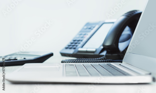 business and communications. Laptop and voip phone in the office, close up of hand. finance graphs. laptop on desk. IP telephony, Cold calling. Audit or accounting. Business Induction banner photo