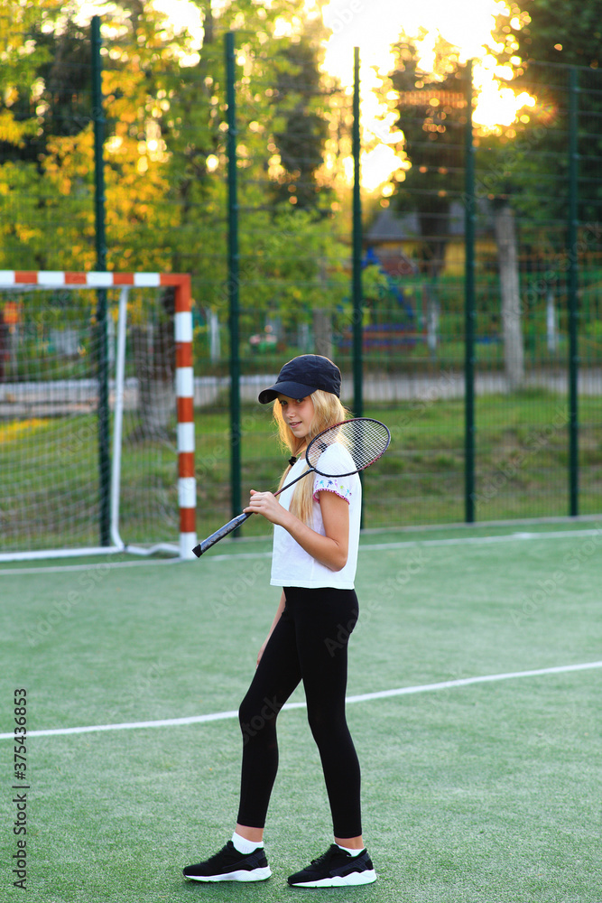 Girl with a racket in her hands on the sports field.