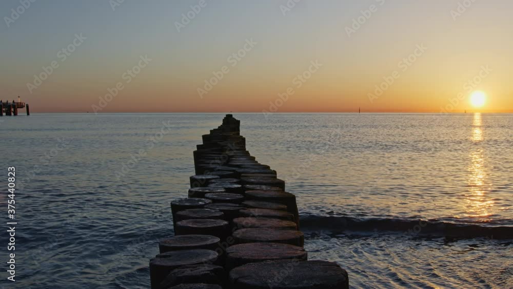 Sunrise at baltic surf with wooden poles in center, slow camera slide to the right, 4k Sunrise at baltic surf with wooden poles in center, slow camera slide to the right, 4k