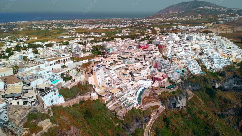 Aerial view towards buildings in a town, on the Santorini island, sunny evening, in Greece - Reverse, tilt up, drone shot Aerial view towards buildings in a town, on the Santorini island, sunny evening, in Greece - Reverse, tilt up, drone shot