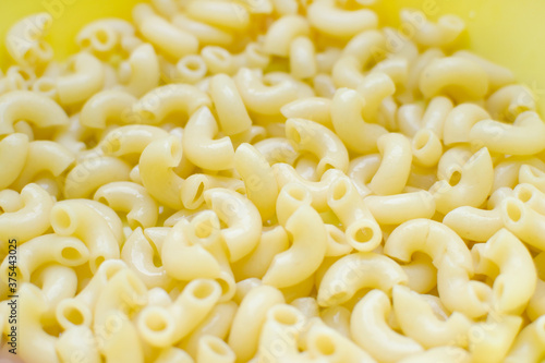 boiled pasta horns without anything close up, yellow background