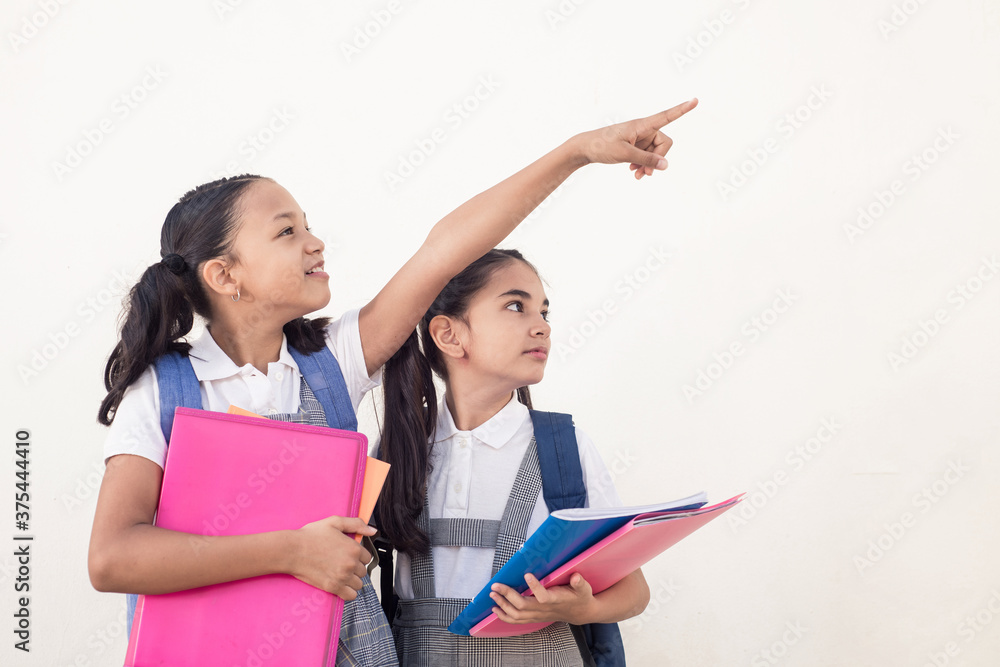 Cute brunette little girl, turn pointing right copyspace, showing something to her friend with copy space for text on isolated white background. Cute brunette little girl, turn pointing right copyspace, showing something to her friend with copy space for text on isolated white background.