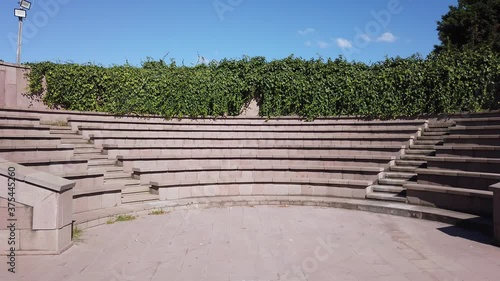 Gray concrete amphitheater in city park. Summer sunny day. Blue bright sky.