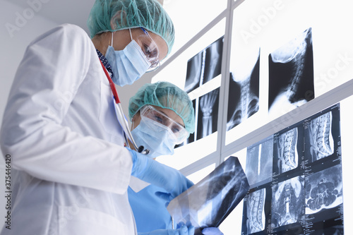 Two medical workers in protective medical masks and gloves and glasses examine X-rays. Internal organs examination concept