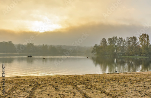 Foggy morning on the beach located on the shore lake.