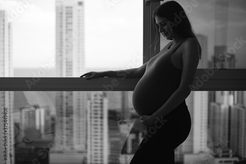 black and white pregnancy woman in the city view window (ID: 375449408)