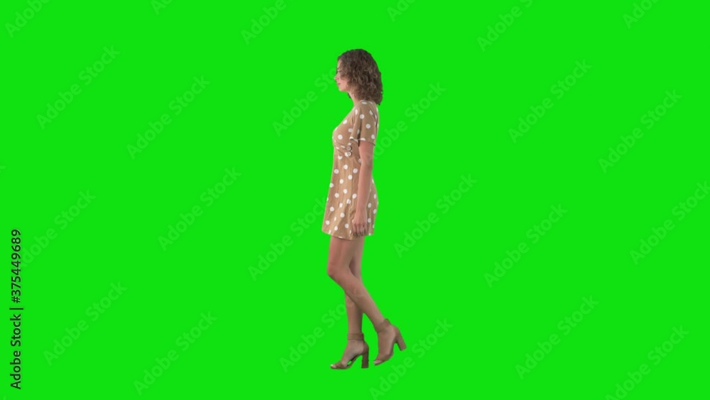 Relaxed young woman in dress and high heels walking side view on chroma key green screen. Relaxed young woman in dress and high heels walking side view on chroma key green screen.
