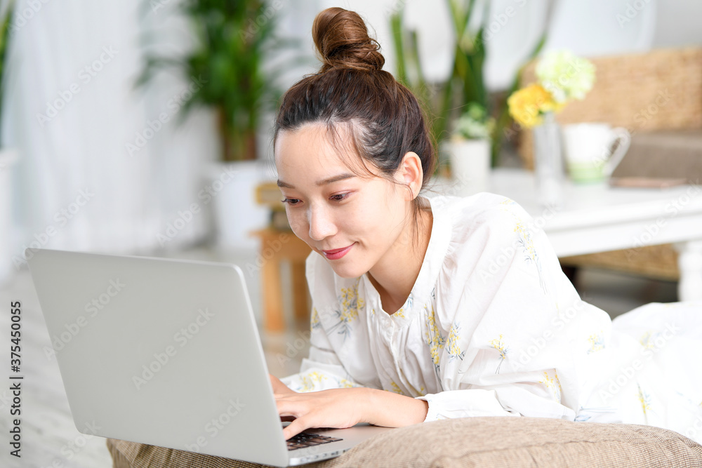 寝ながらパソコンを操作する若い女性