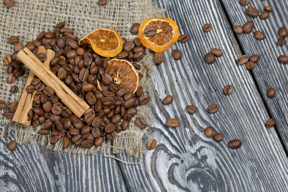 Coffee beans on coarse linen and spices. On a surface of brushed pine boards painted black and white. Coffee beans on coarse linen and spices. On a surface of brushed pine boards painted black and white.
