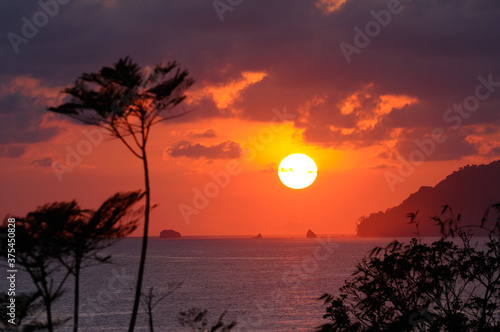 Hot tropical sun setting over the Pacific Ocean at Carate Costa Rica photo