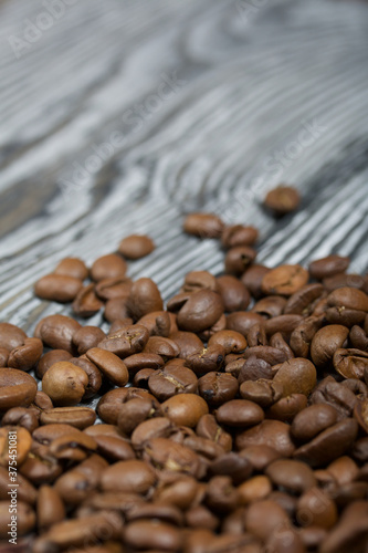 Coffee beans on a black-and-white brushed pine plank surface. Close-up shot.