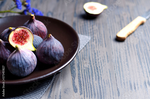Fig fruits and slices on dark plate, with a knife accessory on rustic wooden table
