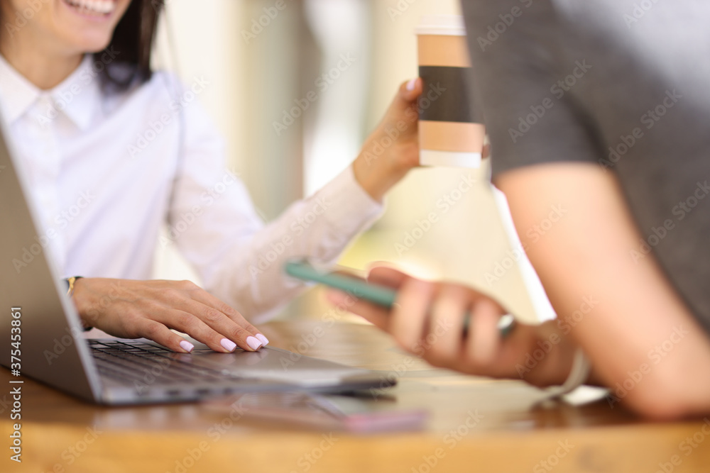Smiling woman in cafe holds a hand on laptop keyboard next to man with smartphone. Business meeting in cafe concept Smiling woman in cafe holds a hand on laptop keyboard next to man with smartphone. Business meeting in cafe concept
