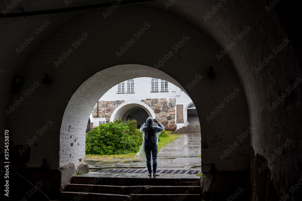 a woman in a transparent raincoat in the rain against the background of an ancient fortress-monastery on the Solovetsky Islands