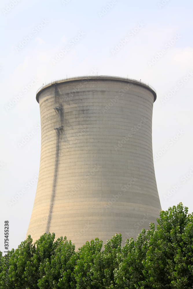 heavy industrial water cooling tower and the green tree