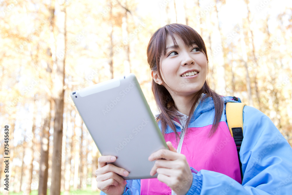 Fototapeta premium タブレットPCを見ながら山登りする女性