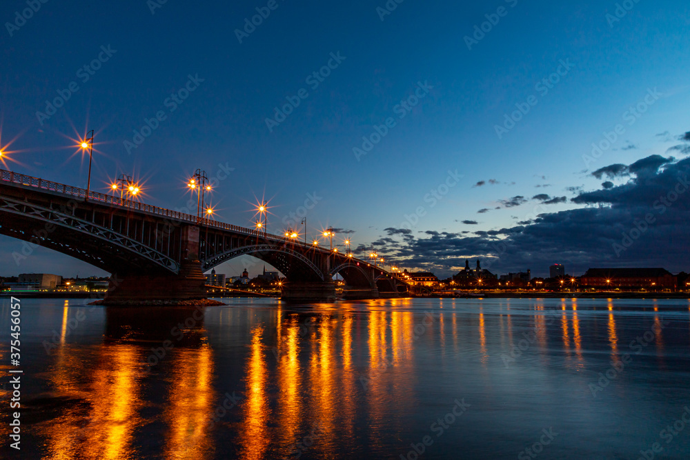 The illuminated Theodor Heuss Bridge that crosses the Rhine between Mainz and Wiesbaden at night. In the background the silhouette of Mainz