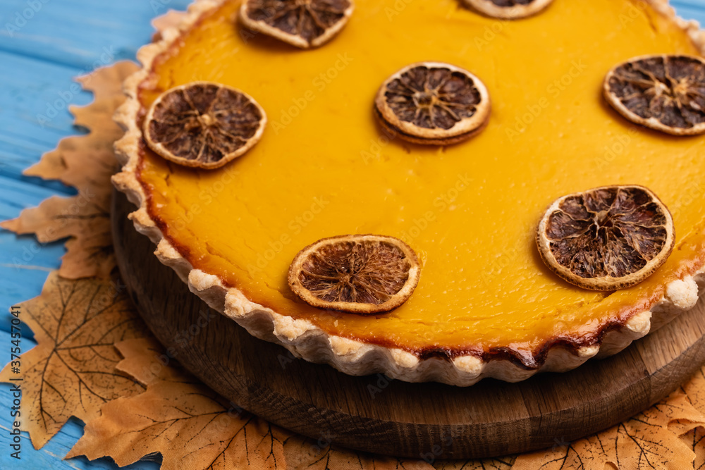close up view of decorated pumpkin pie with golden foliage on blue wooden background close up view of decorated pumpkin pie with golden foliage on blue wooden background