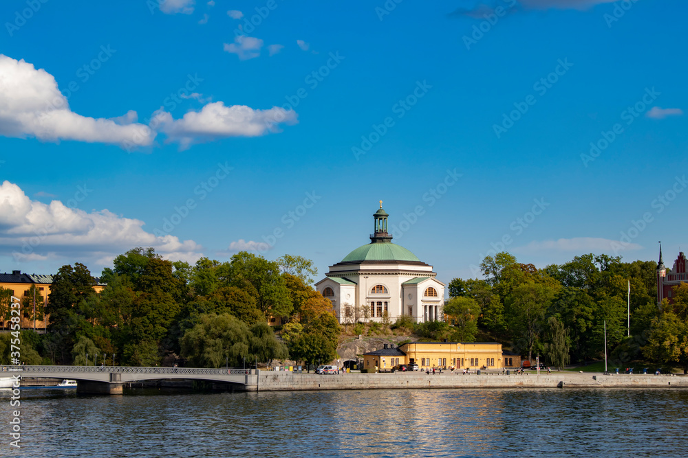 View of the Eric Ericsonhallen Concert Hall Surrounded by Trees rising from the Waterfront in Stockholm, Sweden