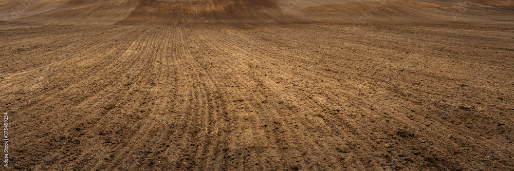 wide panoramic view of arable land with long rows of furrows. autumn or spring hilly cultivated agricultural field. Artistic template for presentation or creative background wide panoramic view of arable land with long rows of furrows. autumn or spring hilly cultivated agricultural field. Artistic template for presentation or creative background