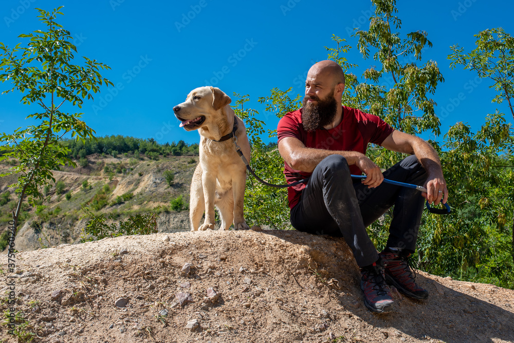 Active young man with his dog on hike resting in the nature
