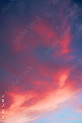 Beautiful summer sunset blue sky with pink clouds. The sun illuminates the sky in such a way that it turns pink and orange. © Ekaterina