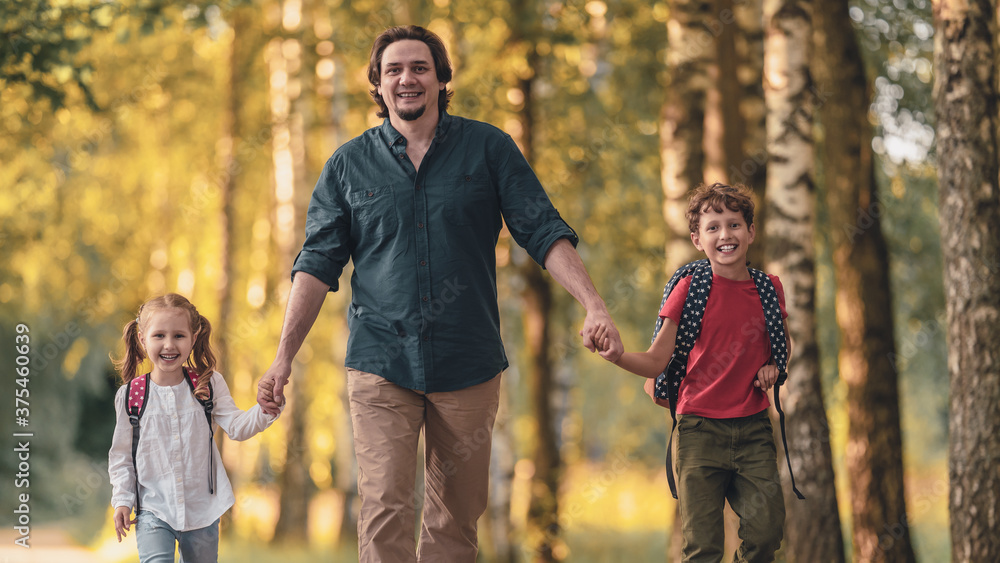 Fototapeta premium Father walks with children, primary school students, after school in autumn Park