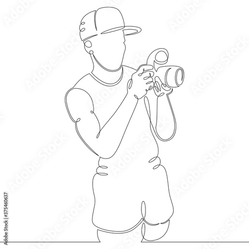a young man photographer in a baseball cap takes a photo camera