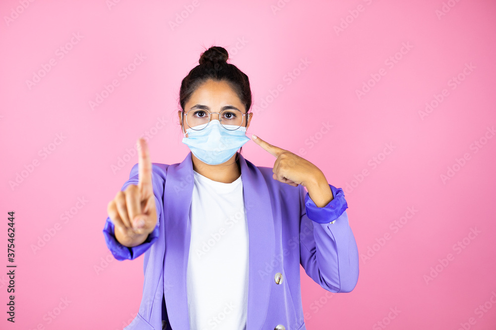 Young beautiful business woman over isolated pink background pointing the mask. Warning expression with negative and serious gesture on the face. Young beautiful business woman over isolated pink background pointing the mask. Warning expression with negative and serious gesture on the face.