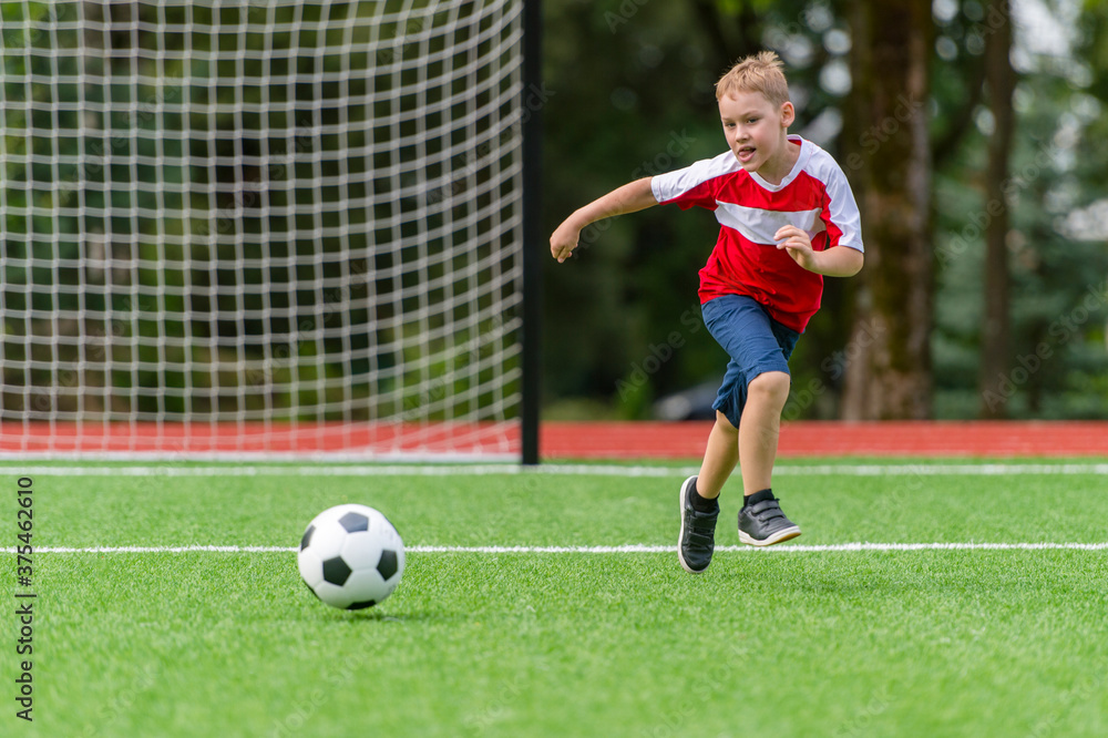 Football soccer training for kids. Boy running and kicking soccer ball. Young boy improving soccer skills Football soccer training for kids. Boy running and kicking soccer ball. Young boy improving soccer skills
