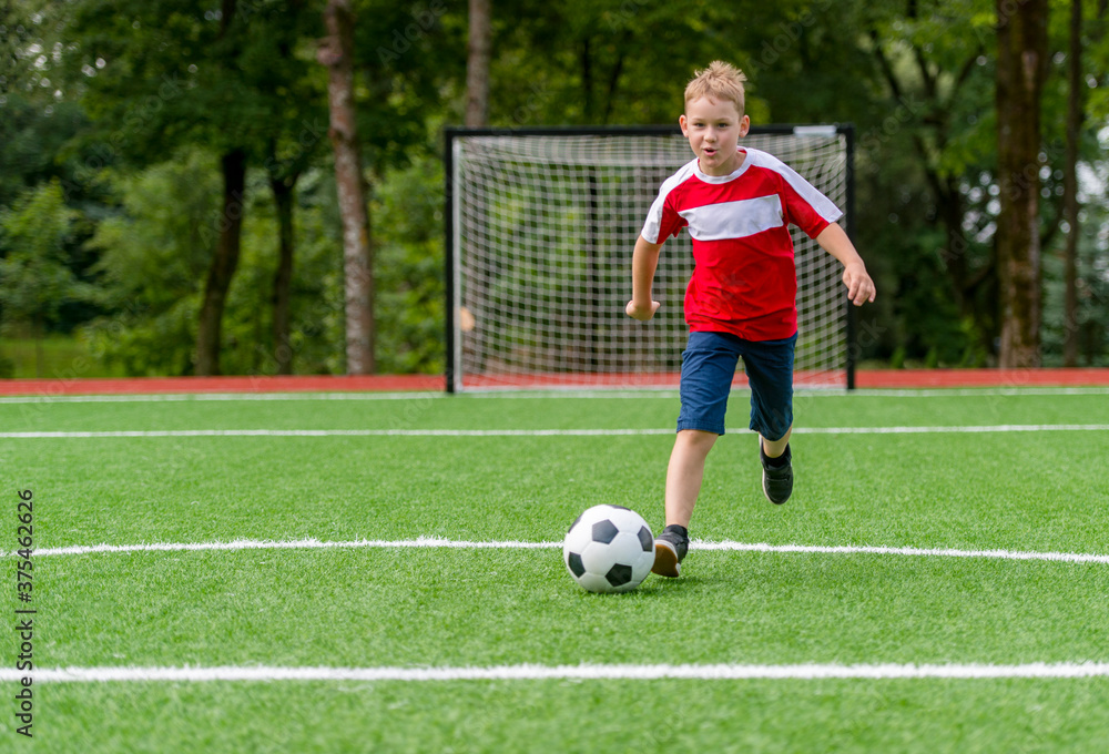 Obraz premium Football soccer training for kids. Boy running and kicking soccer ball. Young boy improving soccer skills