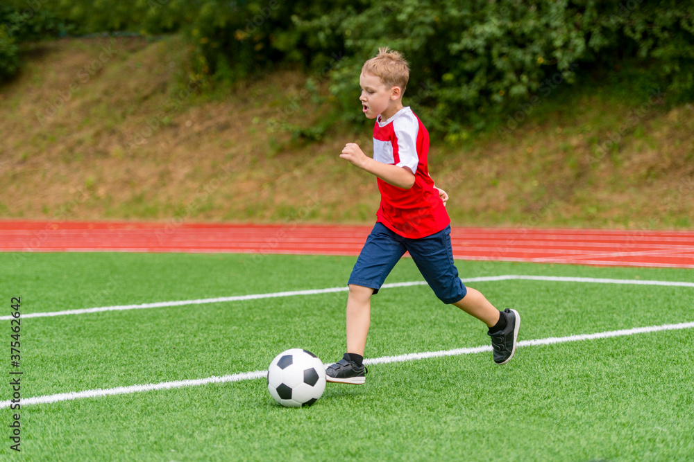 Football soccer training for kids. Boy running and kicking soccer ball. Young boy improving soccer skills