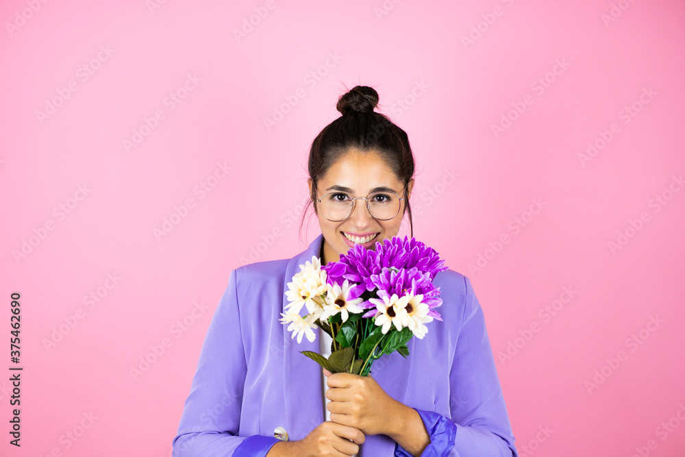 Young beautiful business woman over isolated pink background smiling and smelling a bouquet of flowers Young beautiful business woman over isolated pink background smiling and smelling a bouquet of flowers