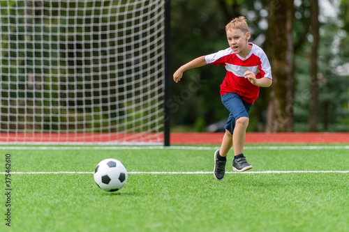 Football soccer training for kids. Boy running and kicking soccer ball. Young boy improving soccer skills © Augustas Cetkauskas