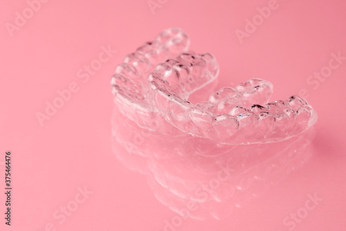 Two Invisible dental teeth aligners on the pink background. Orthodontic temporary removable braces for fixing teeth after alignment. Therapy after brackets. 