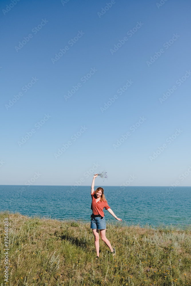 Young Beautiful Girl with Flowers Walking and Dancing on a Beach with smile and joy