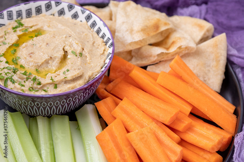 Canvas Print Eggplant Hummus on a Platter of Celery, Carrots, and Pita Bread on a Black Table