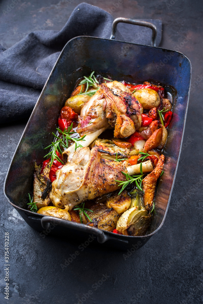 Traditional braised leg of lamb with eggplant, potatoes and tomatoes offered as close-up in a rustic old roasting dish Traditional braised leg of lamb with eggplant, potatoes and tomatoes offered as close-up in a rustic old roasting dish