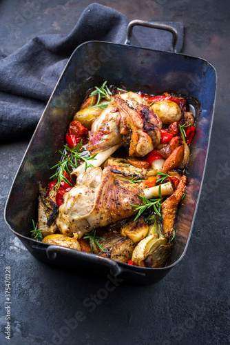 Traditional braised leg of lamb with eggplant, potatoes and tomatoes offered as close-up in a rustic old roasting dish photo