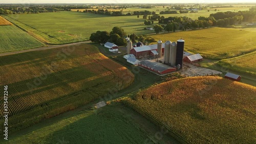 Establishing shot of farmhouse. Aerial view of farm, red barns, corn field in September. Harvest season. Rural landscape, american countryside. Sunny morning