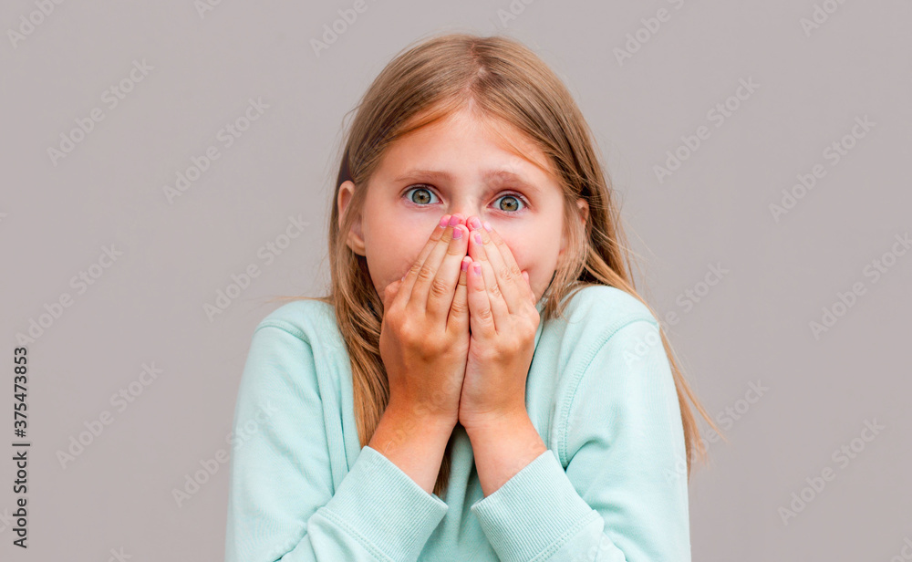 Young woman closing her mouth and wide open eye isolated on gray background Young woman closing her mouth and wide open eye isolated on gray background