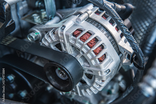 new car generator and belt tensioned on the shaft at shallow depth of field