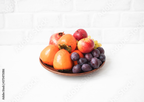 Autumn composition with fresh fruits. Apple, plum, melon, persimmon, pomegranate, grapes. Selective focus.