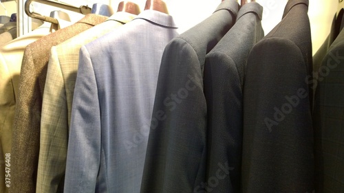Stylish expensive men's business suits for sale. Clothes on hangers. Fashion for managers and businessmen concept. Premium store. 